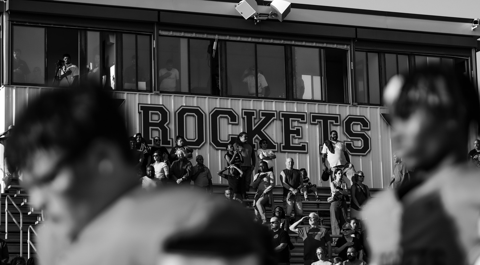 Football players in the foreground with Rockets pressbox in the background.