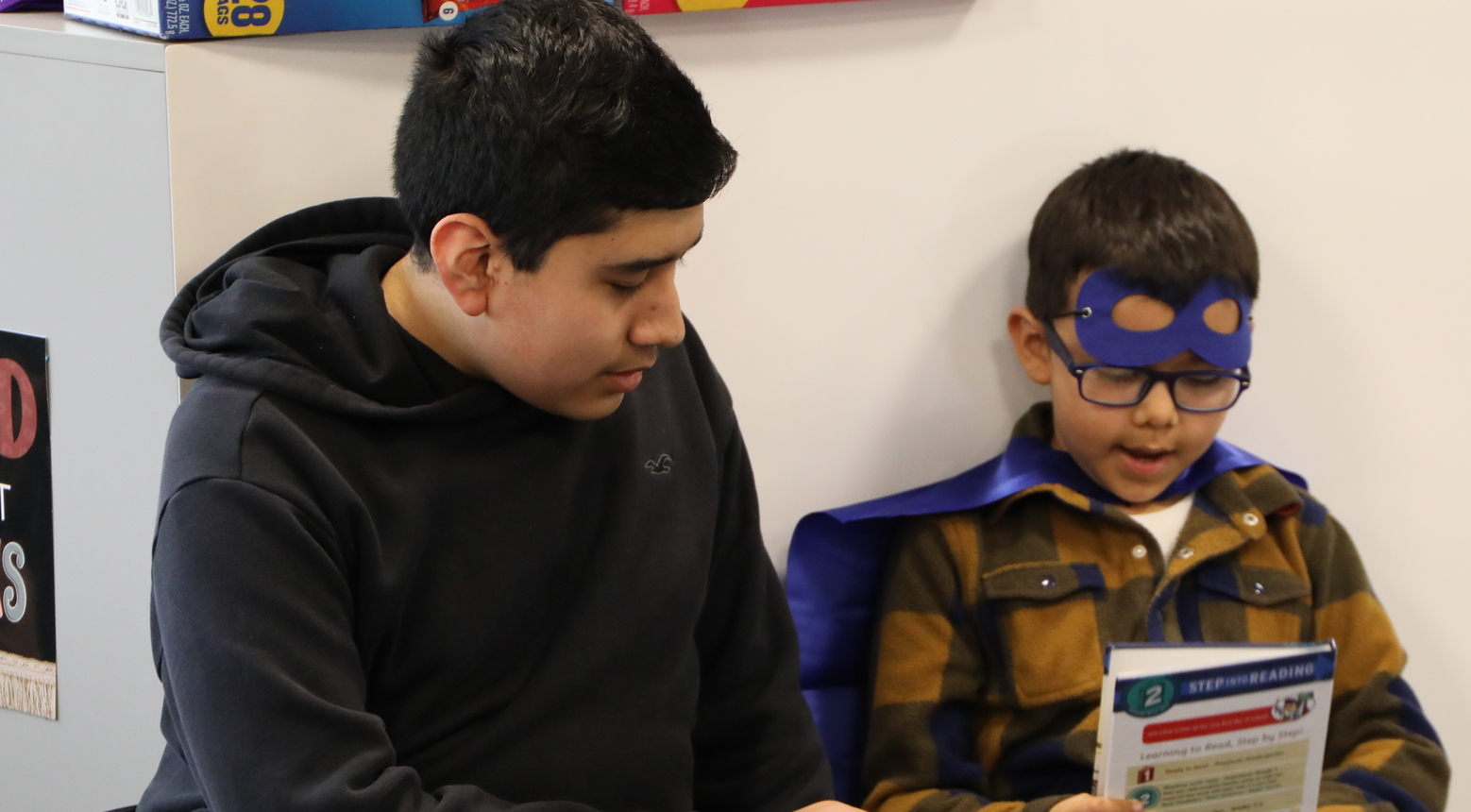 High school student reading to elementary student.