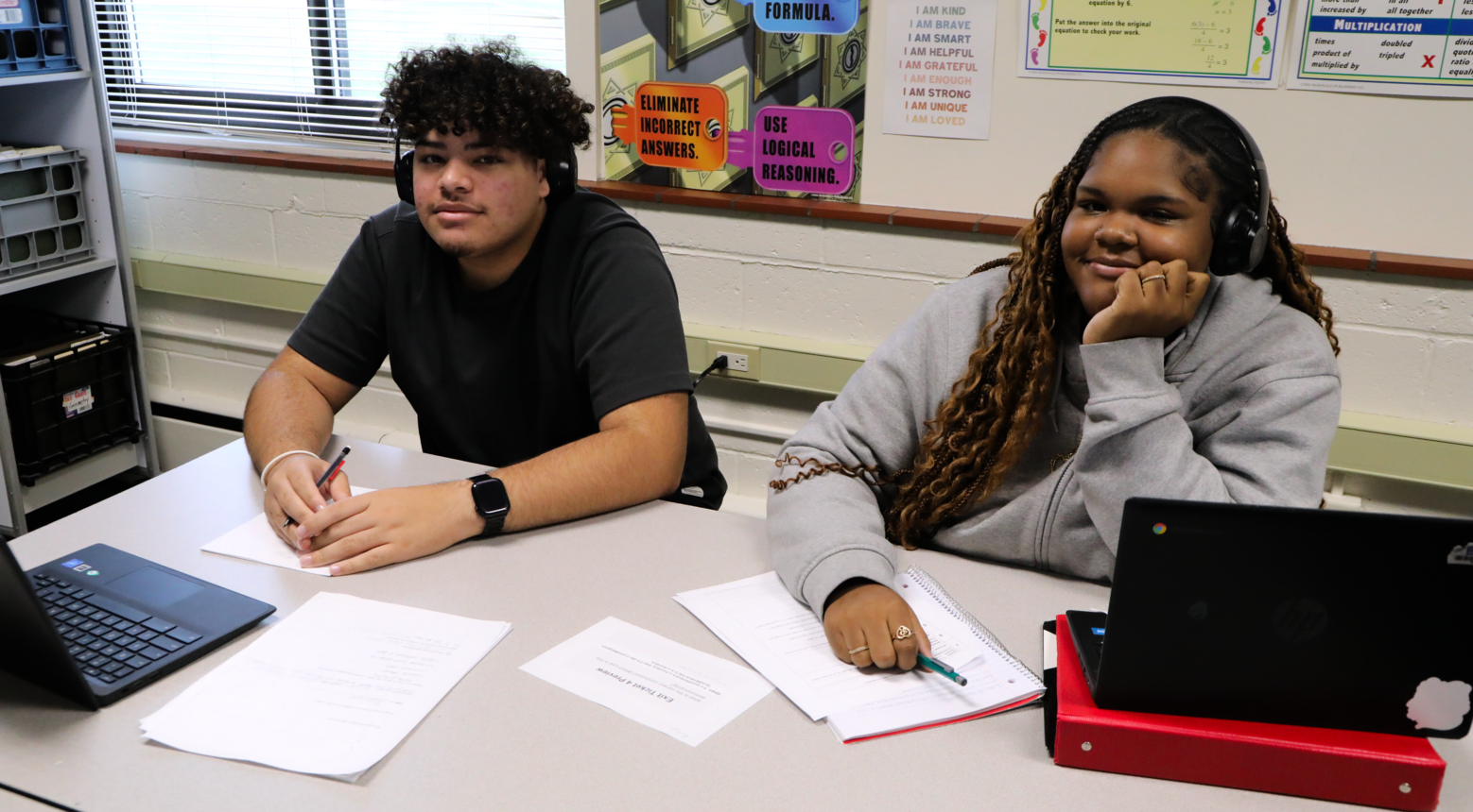 Two students working on their assignment sitting at a table together.