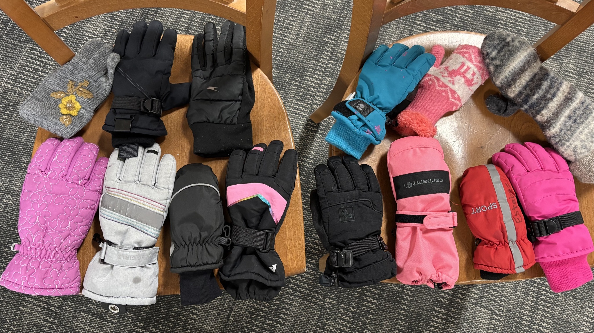 Winter gloves laid out on two chairs.