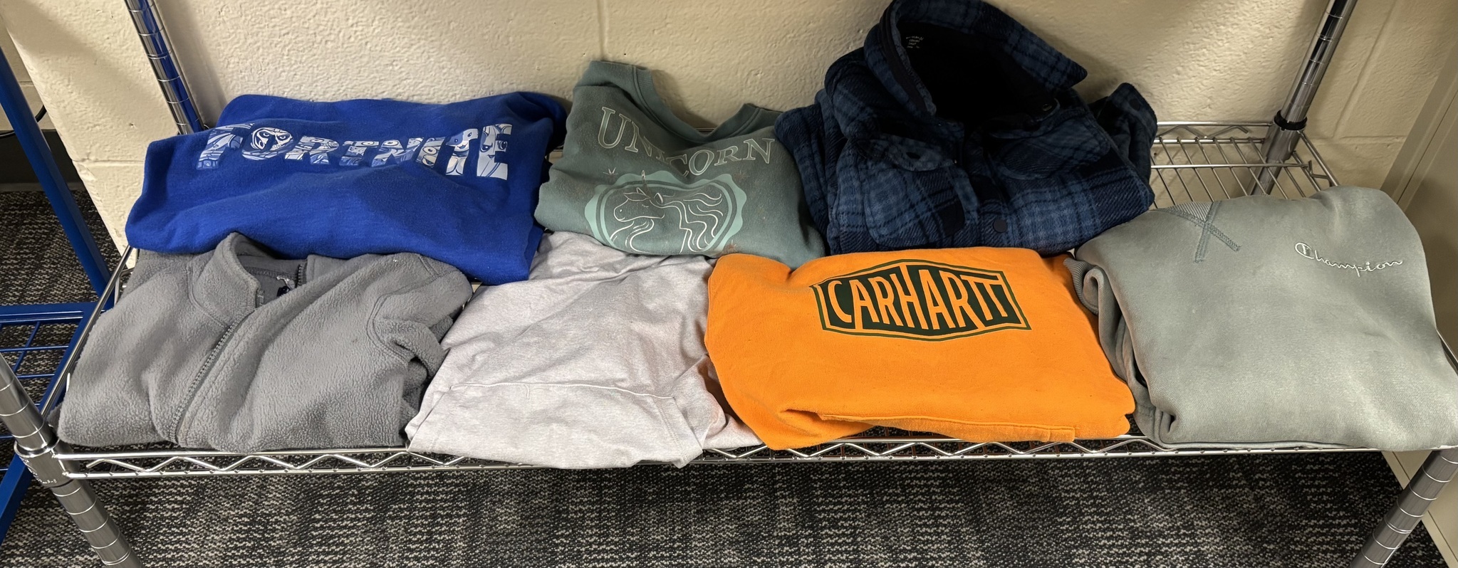 Student sweatshirts folded on a wire rack.