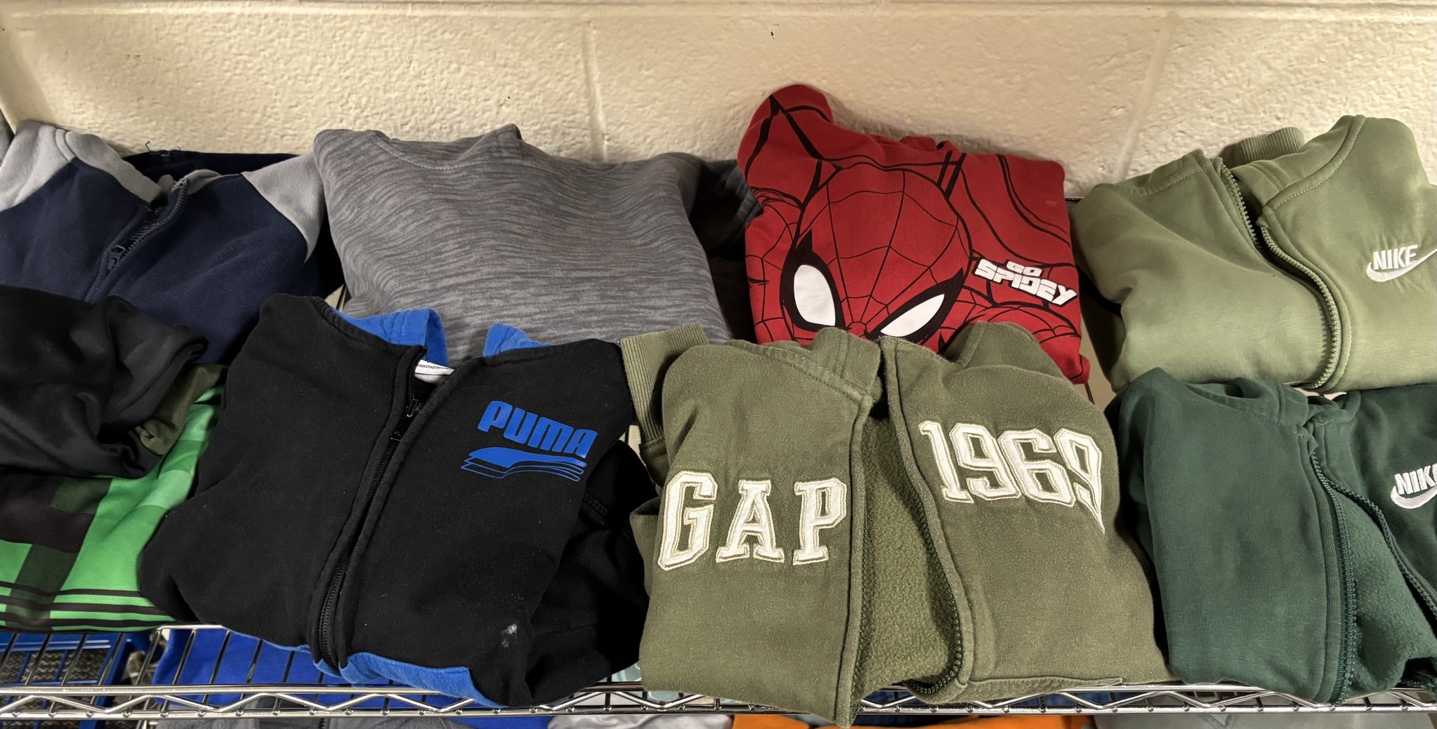 Student sweatshirts folded on a wire rack.
