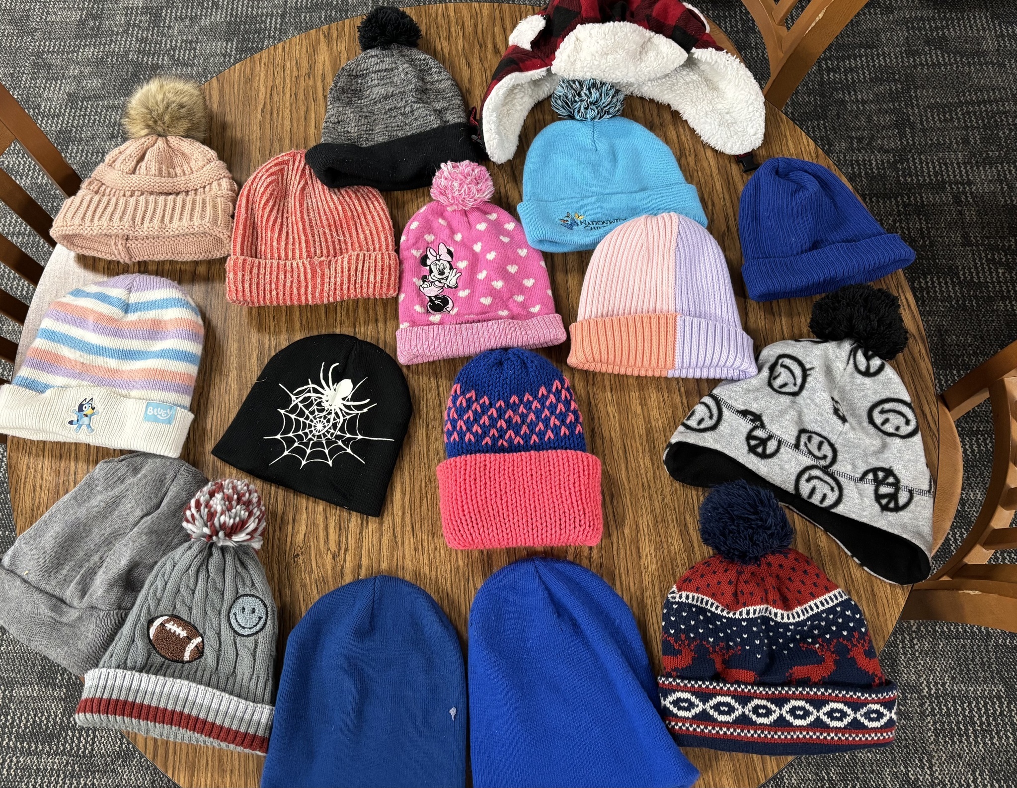 Winter hats laid out on a large table.