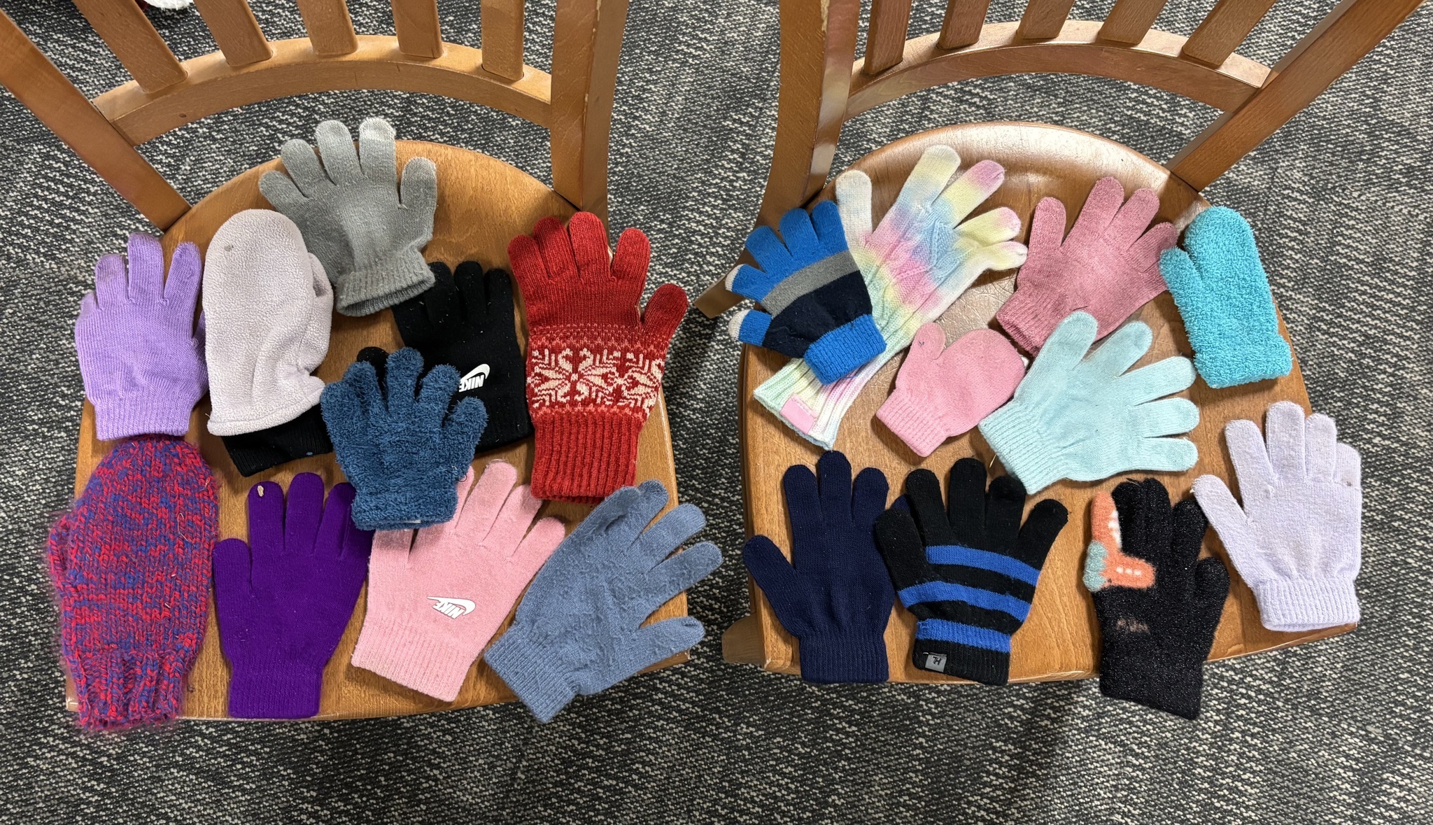 Winter gloves laid out on two chairs.